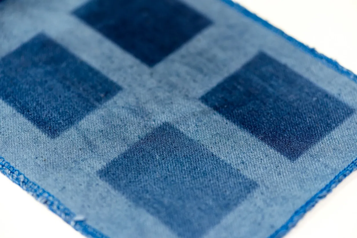 Denim fabric with a pattern of light and dark squares created by localized bleaching